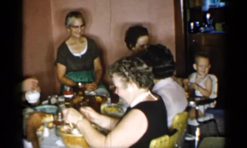 1955: New York. A Group Of People Sitting Around A Table Eating Food.