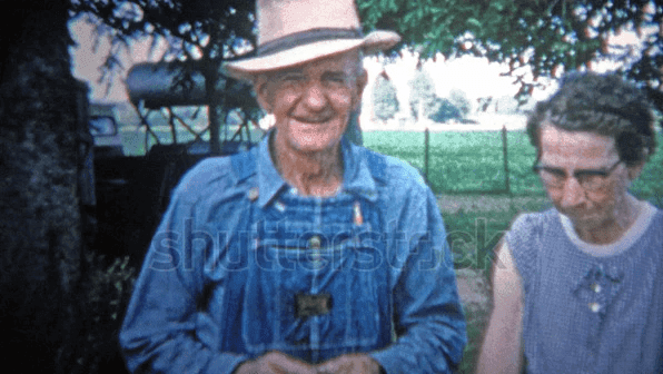 Old farmer and wife in front of family farm.