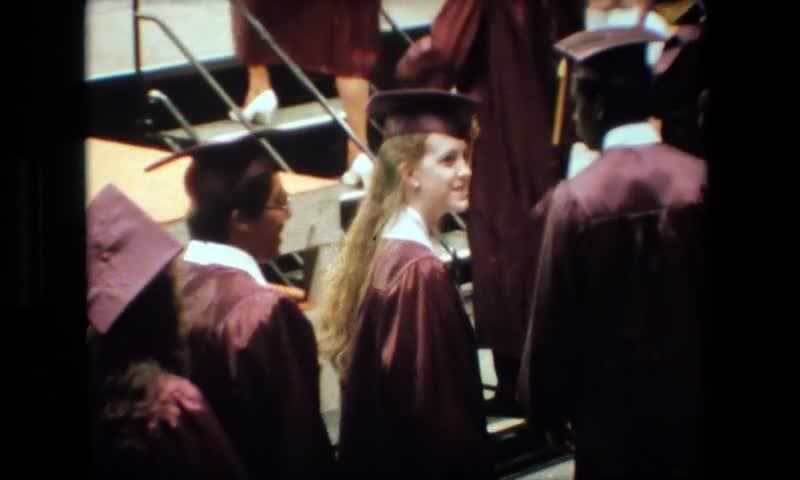 1983: Lansing Michigan. A Group Of People Standing Next To Each Other In Graduation Gowns.