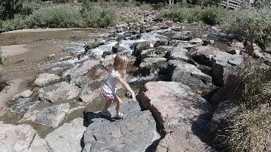 Little Girl Crossing the Rocky Flowing Water