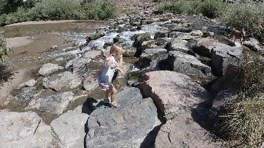 Toddler Climbing Rocks in Urban Stream. Denver, Colorado