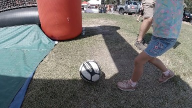 Little kid kicking soccer ball at carnival. Denver, Colorado.