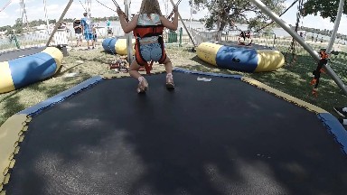 Girl landing on inflatable jumper at park. Denver, Colorado.