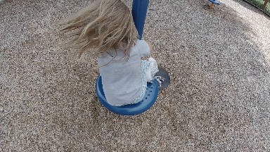 Little Girl Spins on a Playground Toy