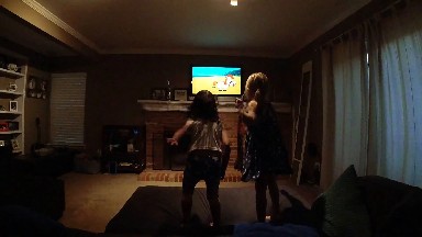 Two Girls Standing In A Living Room Playing A Video Game