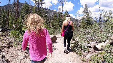 Two Women Walking Down A Trail In The Woods