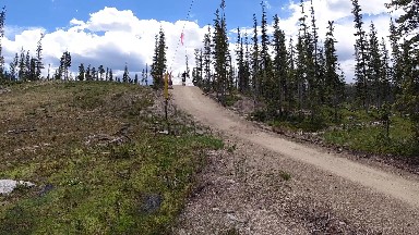 Dirt Road Going Up A Hill With A Sign On It