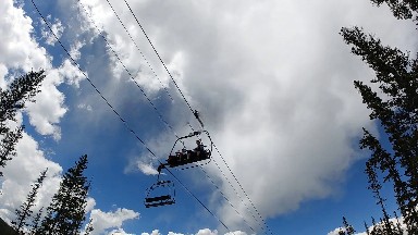 People Riding A Ski Lift In The Sky On A Cloudy Day