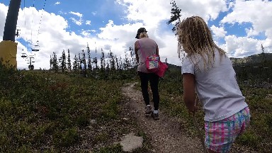 Two Girls Walking Down A Trail With A Backpack On