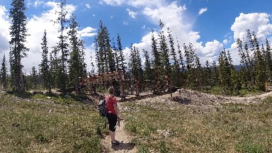 Woman Walking On A Trail In The Mountains With A Backpack