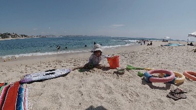 Woman Sitting On The Beach With A Bucket And Toys