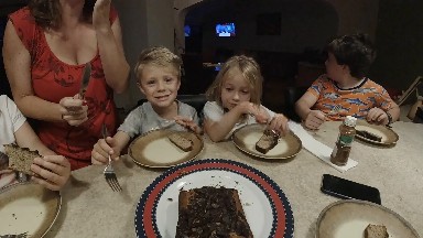 A Lot Of Children Sitting At A Table Eating