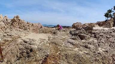 Woman Walking On A Rocky Beach Near The Ocean