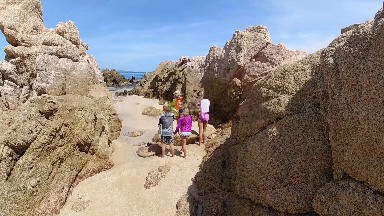 Three Children Are Standing On A Rocky Beach Near The Ocean