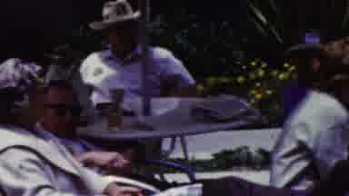 California USA (1961): Several Older People Sitting Outside Underneath An Umbrelaa