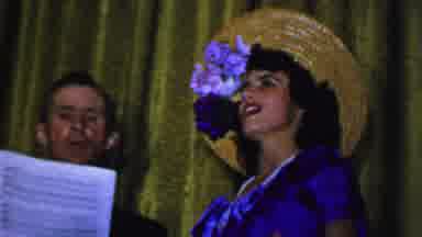 Dallas Texas USA-1956: A Woman in Blue and Floral Hat Sings on Stage with a Man Reading Sheet Music