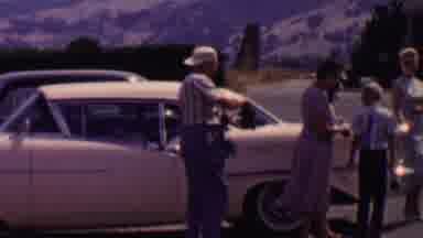 Solvang California USA (1955): A Man Hands A Woman A Bottle Outside