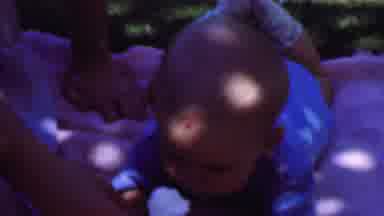 San Diego California USA (1961): Woman Feeds Baby Under A Tree On A Purple Blanket