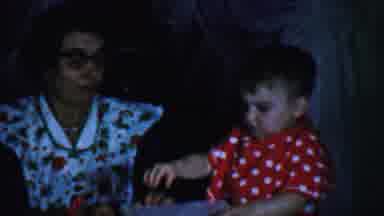 Omaha Nebraska USA (1959): Child Opening Package With Family Watching.