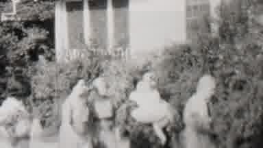 Trenton New Jersey USA-1937: People Walking In Front Of Tall Bushes Outside A