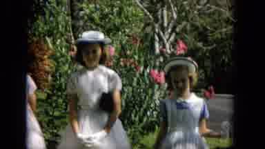 HAWAII-1965: Three Girls in White Dresses and Hats Stand in Front of Green Bushes