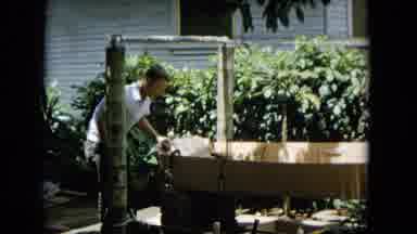 Hawaii (1965): A Man Standing In A Yard Lifts A Power Drill Out Of A Building