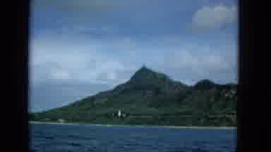 1965: Molokai Island View From Boat With White Tower And Green Mountains