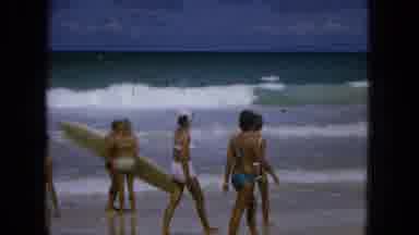 1965: Women Walking on Beach with Surfboard, Children Playing in Sand