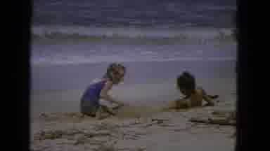 1965: Two Girls Playing In Sand At Beach With Waves