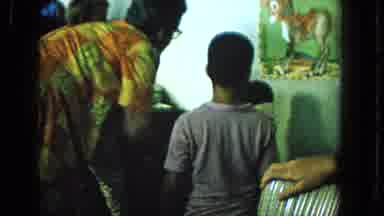 1965:EASTER MOLOKAI WHALES BEACH PARADE ALOHA TOWER. An Older Woman Guiding A
