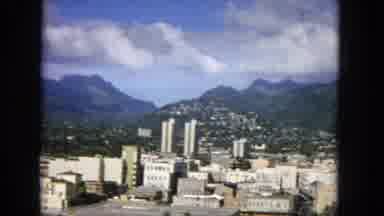 1965: Hawaiian Cityscape with Mountains and High-Rise Towers