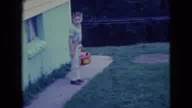 Wellsburg Iowa (1965): Boy With Gas Can Waves As Man Finishes Cutting Grass Near