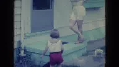 Wellsburg Iowa (1965): Little Girl Being Watched By Adult Female As Puppy Runs Up