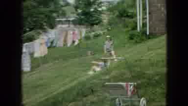 WELLSBURG IOWA-1965: Child Sliding Down A Small Hill While Other Children Watch