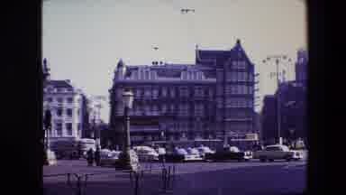Amsterdam Netherlands (1967): Cars Approaching Intersection With View Of Building