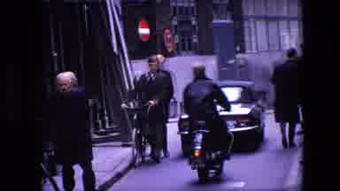 Amsterdam Netherlands (1967): Man Rides Motorcycle Behind Car Down Narrow Street