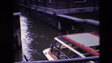 Amsterdam Netherlands (1967): An Enclosed Passenger Boat Motors Down An Urban