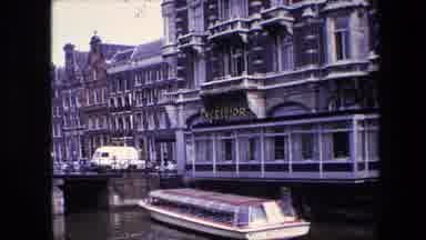 Amsterdam Netherlands (1967): Pan Of 1960s City With River And A Boat