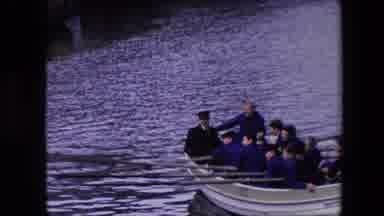 Amsterdam Netherlands (1967): People Rowing A Large Boat Near A City By The River.