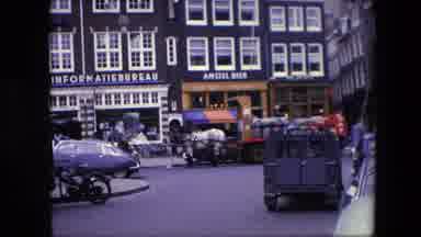 Amsterdam Netherlands (1967): People Walking By As A Volkswagon Bug Enters A