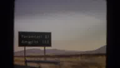 Arizona (1967): Riding In A Car Past Open Fields And A Highway Sign