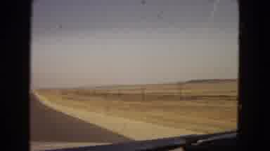 Arizona (1967): Driving On An Open Road Followed By Several People And A Pet