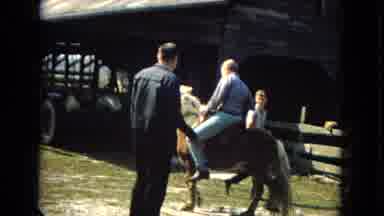 ARIZONA-1967: Young Man Rides A Pony Beside A Barn While Another Man And Young