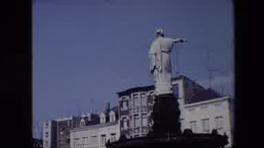 Brussels Belgium-1967: Statue Atop Fountain Pointing Toward City Buildings
