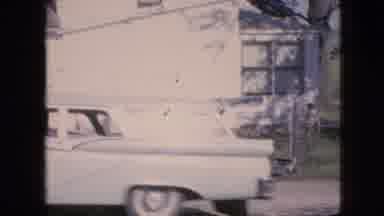 Iowa USA (1967): Woman Walking From Behind Car Toward Camera