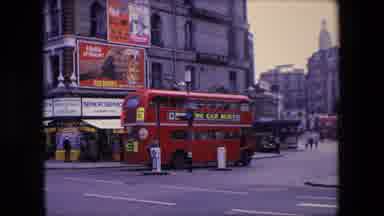 London England (1967): British Double-Decker Bus Turns The Corner Of A Large