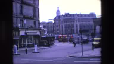 London England (1967): Two People Crossing An Empty Street As A Car Drives By