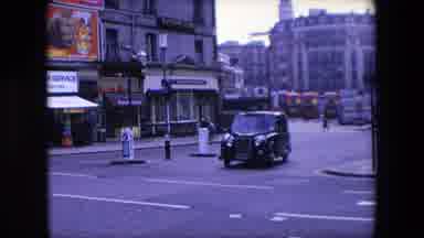 London England (1967): Black Car Turns Normal Speed Around The Corner With In A