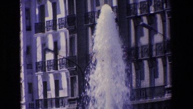 Madrid Spain (1967): A Water Fountain Gushes Upward In Front Of A Multiple-Story