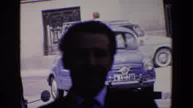 Madrid Spain (1967): Man In Front Of An Old Vehicle With A Woman Passing By